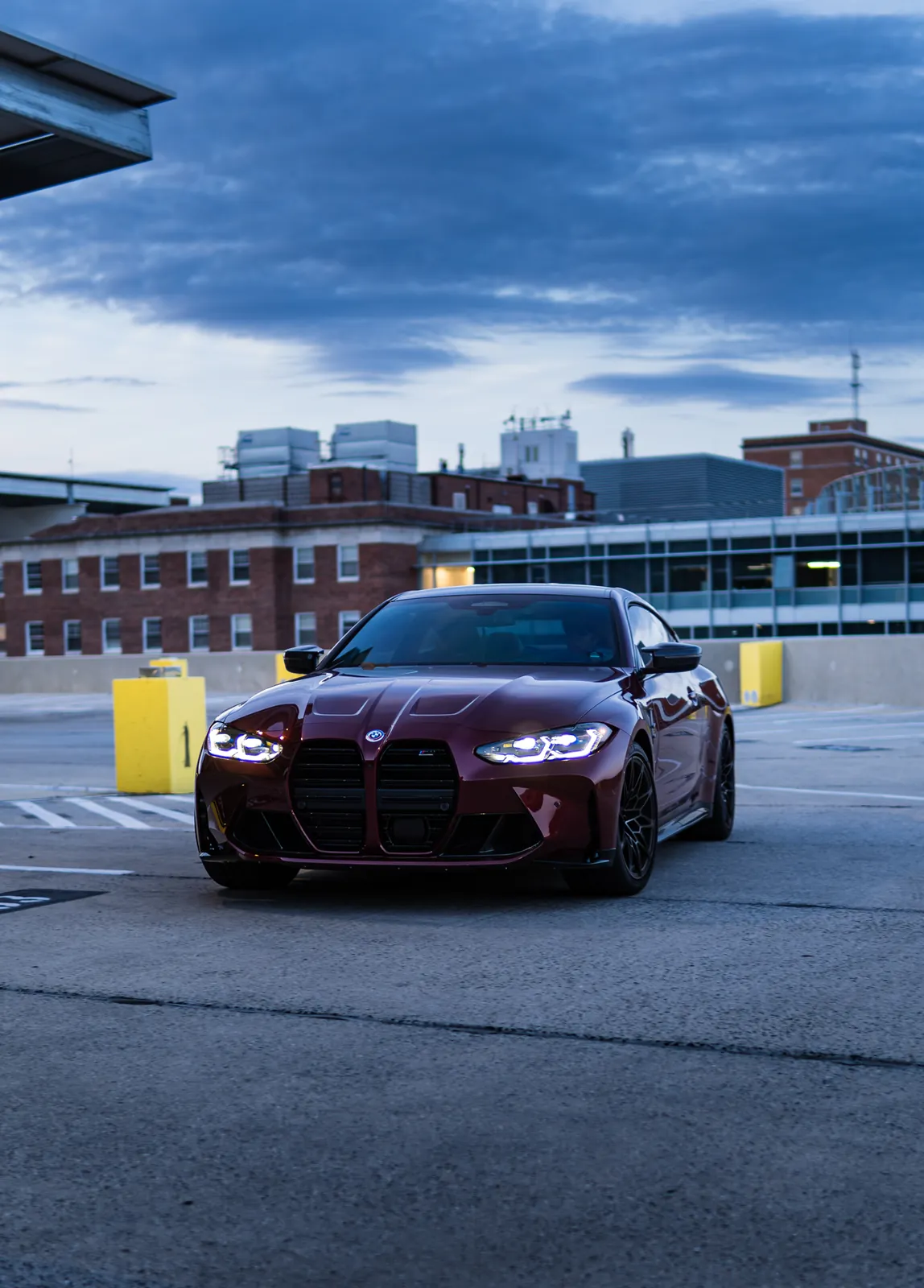 Red BMW M4 on a parking garage with blue cloudy sky
