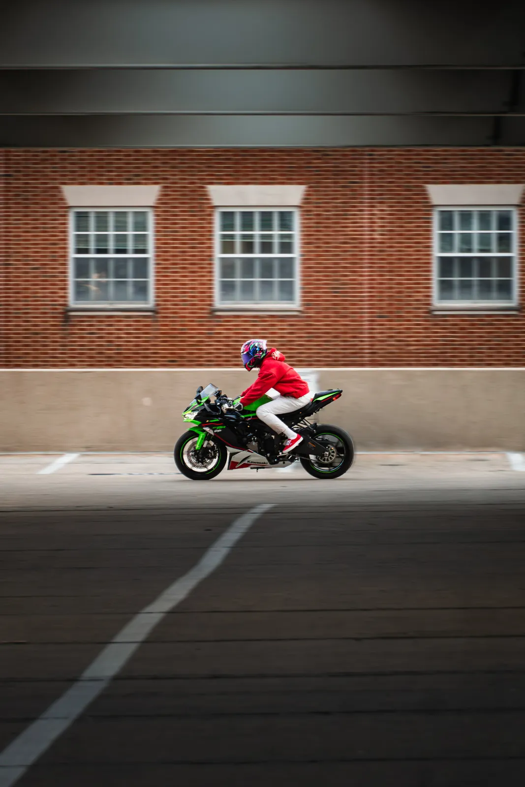 Rider on green Kawasaki Ninja moving in a parking garage