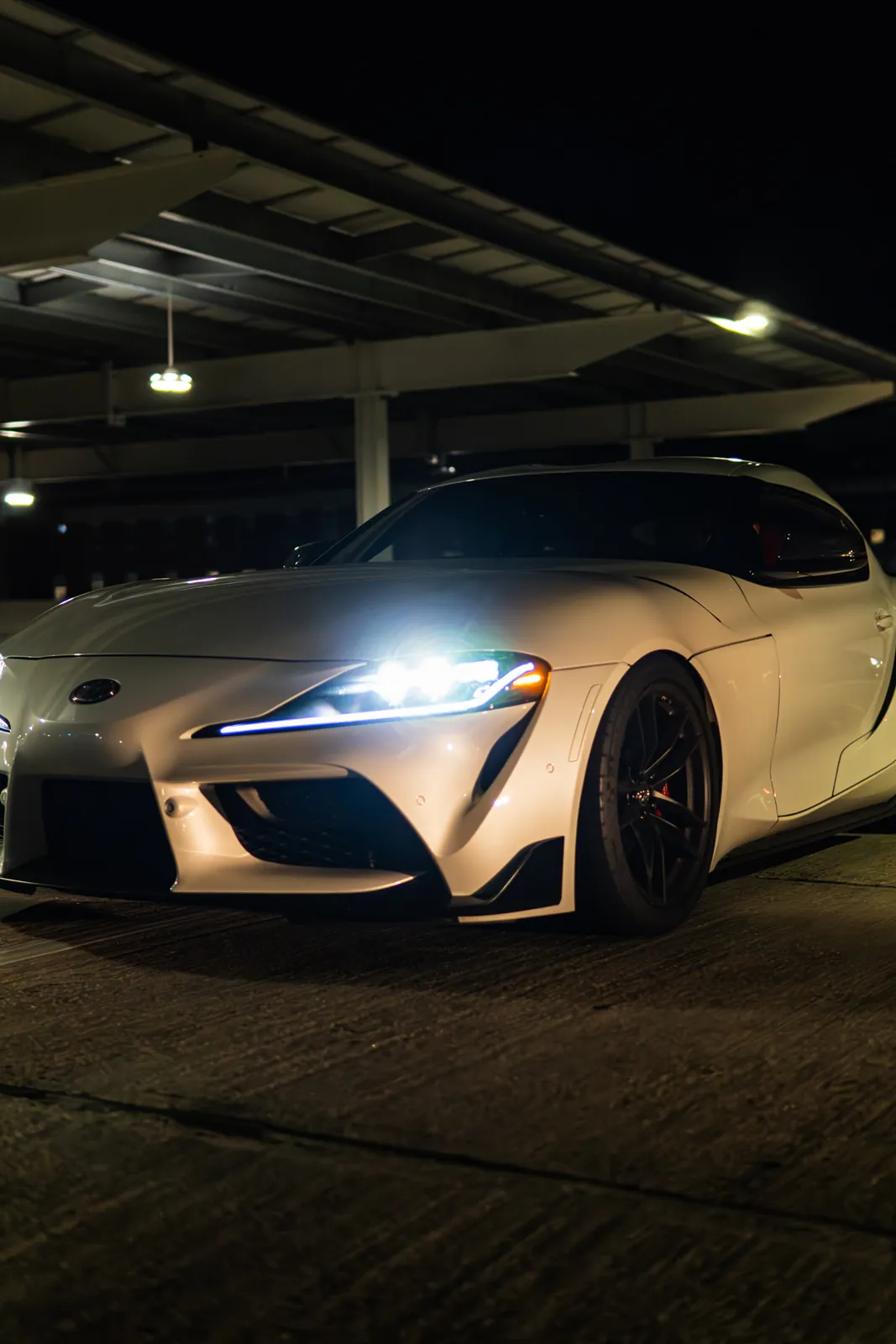 Close-up of a moving white Supra headlight in a parking garage