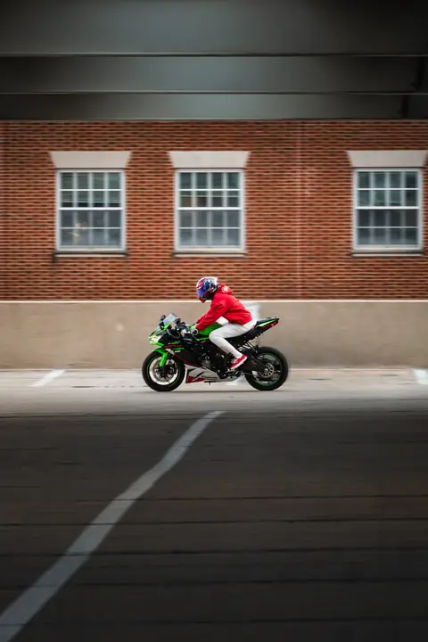 Rider on green Kawasaki Ninja moving in a parking garage