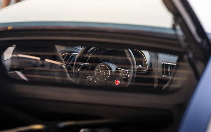 Zoomed into the steering wheel from the back window of a White Audi R8